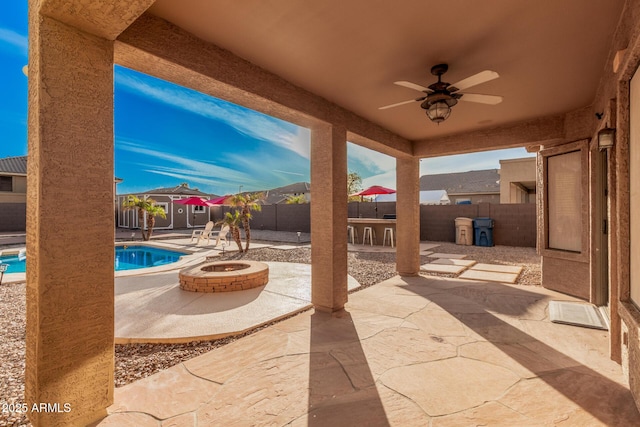 view of patio featuring a fire pit, a fenced in pool, and ceiling fan