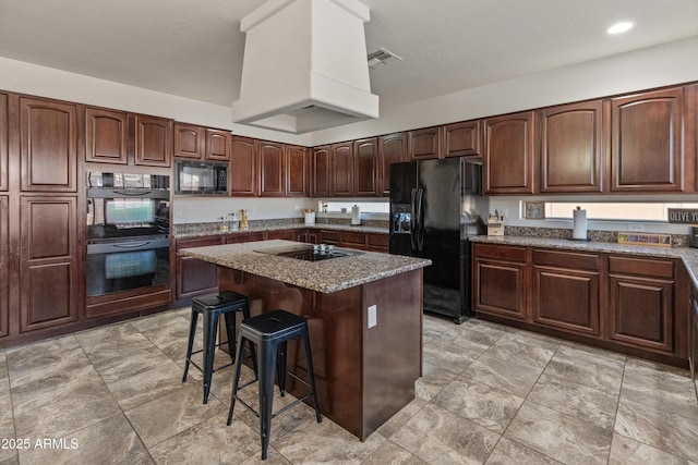 kitchen featuring black appliances, a breakfast bar, stone countertops, a kitchen island, and custom exhaust hood