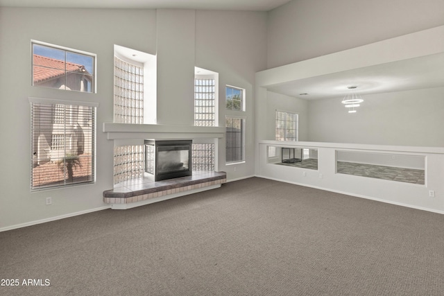 5917 N 133rd Ave, Litchfield Park, AZ 85340 - unfurnished living room with dark colored carpet, baseboards, a glass covered fireplace, and a towering ceiling