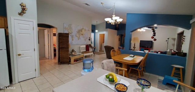 dining space with tile patterned floors, a chandelier, and vaulted ceiling