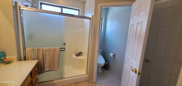 bathroom featuring tile patterned flooring, vanity, toilet, and a shower with door