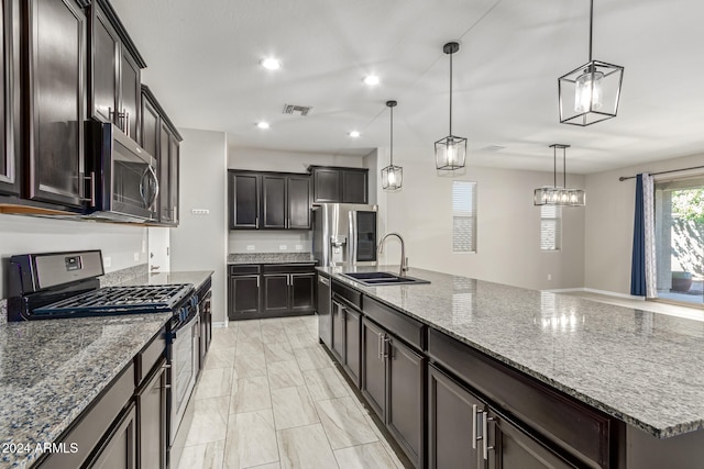 kitchen featuring a large island with sink, sink, pendant lighting, dark brown cabinetry, and stainless steel appliances