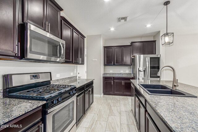 kitchen featuring sink, appliances with stainless steel finishes, dark brown cabinetry, and decorative light fixtures