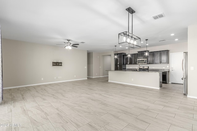 kitchen with a kitchen island with sink, hanging light fixtures, sink, appliances with stainless steel finishes, and ceiling fan