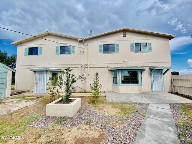 rear view of house with a patio area, an outdoor structure, and fence