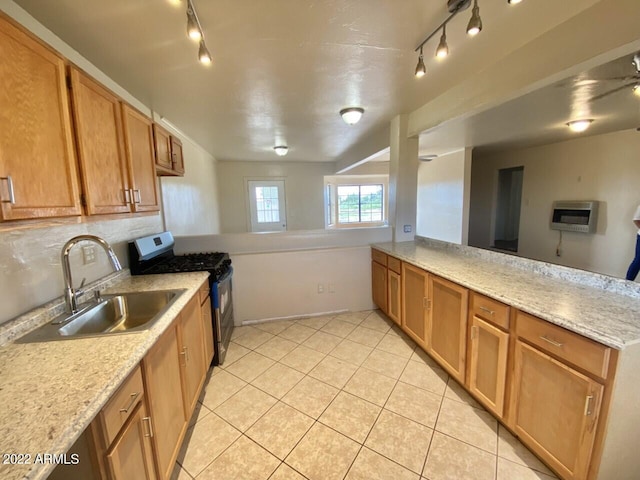 kitchen with kitchen peninsula, stainless steel range with gas cooktop, track lighting, light tile floors, and sink