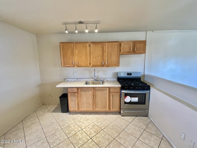 kitchen featuring stainless steel gas range oven, track lighting, sink, and light tile floors