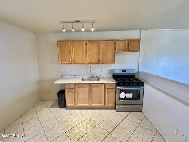 kitchen with light countertops, a sink, brown cabinets, light tile patterned floors, and gas range