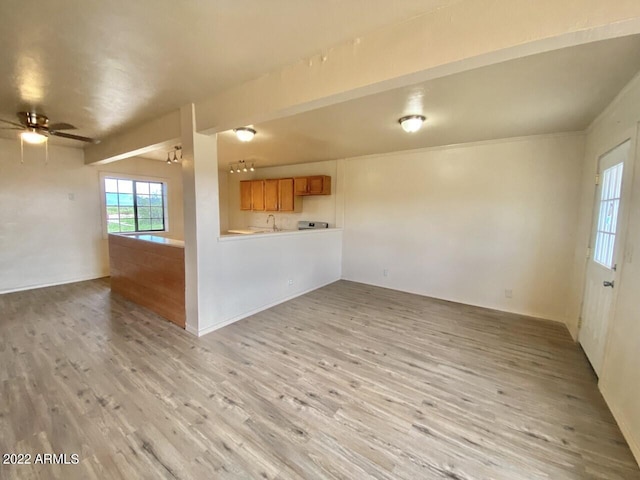 unfurnished living room featuring wood-type flooring, sink, and ceiling fan