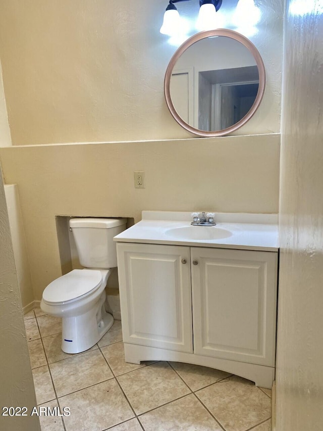 half bath featuring toilet, tile patterned flooring, and vanity