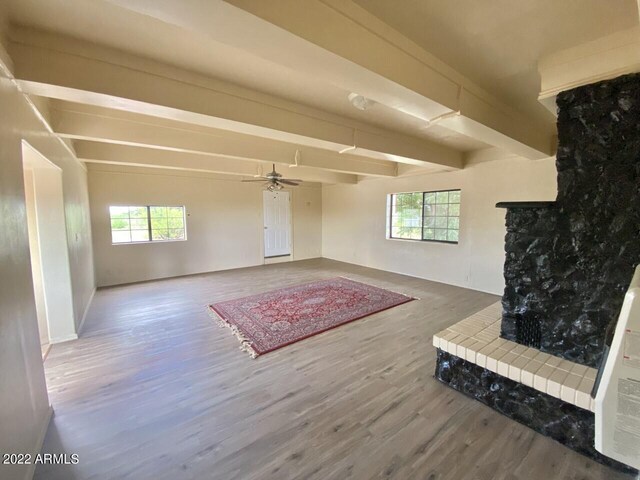 interior space with hardwood / wood-style floors, ceiling fan, beam ceiling, and a tile fireplace