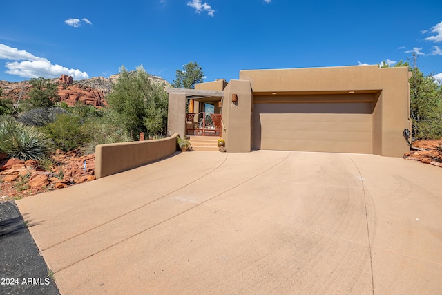 pueblo-style home with stucco siding, concrete driveway, and an attached garage