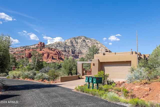 view of front facade with stucco siding, driveway, a mountain view, and an attached garage