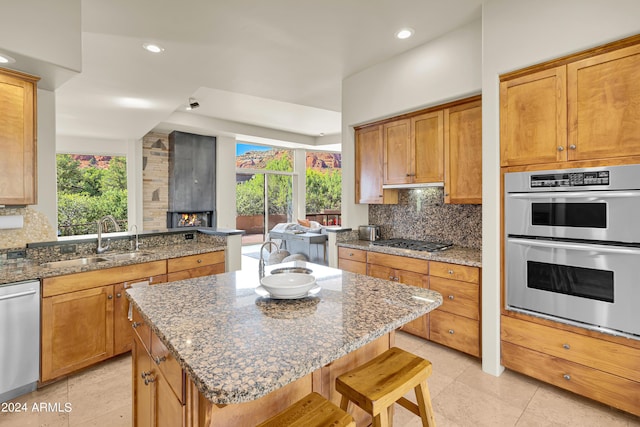 kitchen featuring dark stone countertops, backsplash, appliances with stainless steel finishes, and a sink