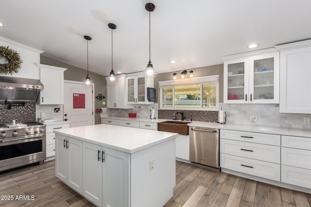 kitchen with a center island, decorative backsplash, appliances with stainless steel finishes, decorative light fixtures, and white cabinetry