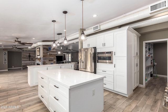 kitchen featuring white cabinetry, hanging light fixtures, a kitchen island, and stainless steel appliances