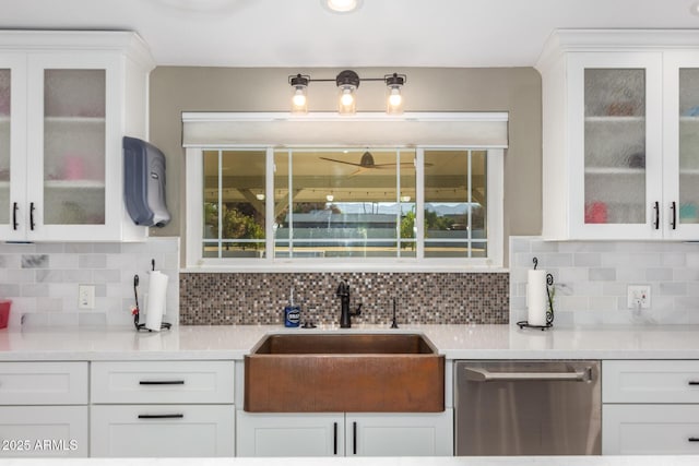 kitchen with stainless steel dishwasher, backsplash, white cabinets, and sink