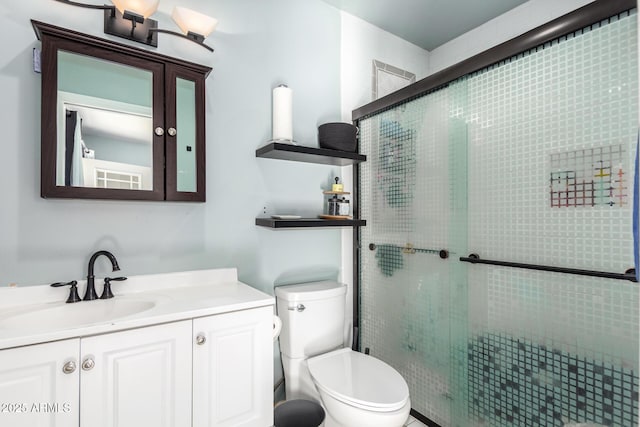 bathroom featuring vanity, toilet, and a shower with door