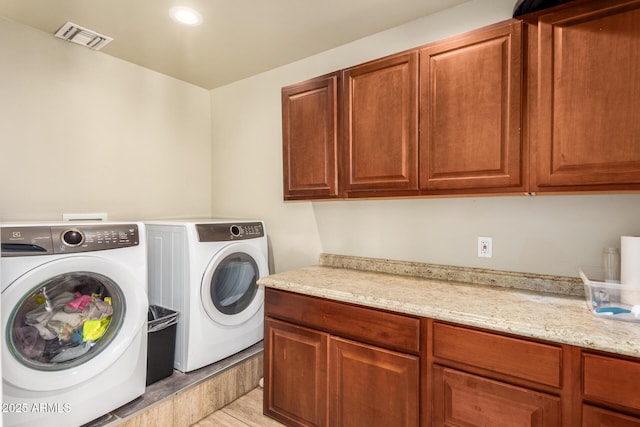 laundry area featuring cabinets, light tile patterned floors, and washing machine and dryer