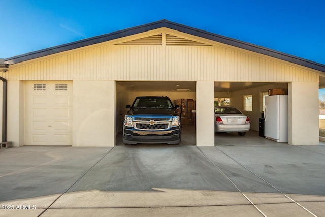 garage featuring white fridge and a carport