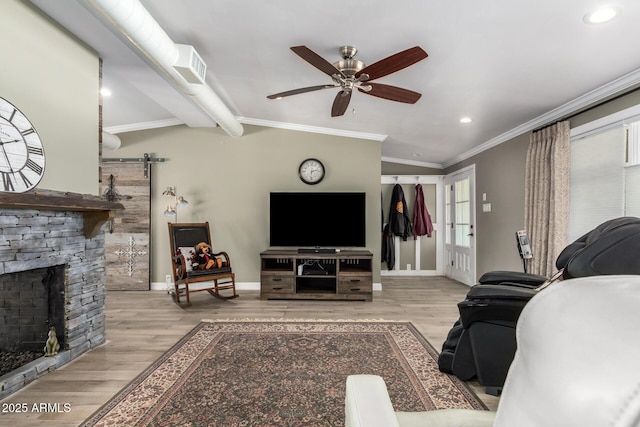 living room with light wood-type flooring, ceiling fan, crown molding, a stone fireplace, and lofted ceiling