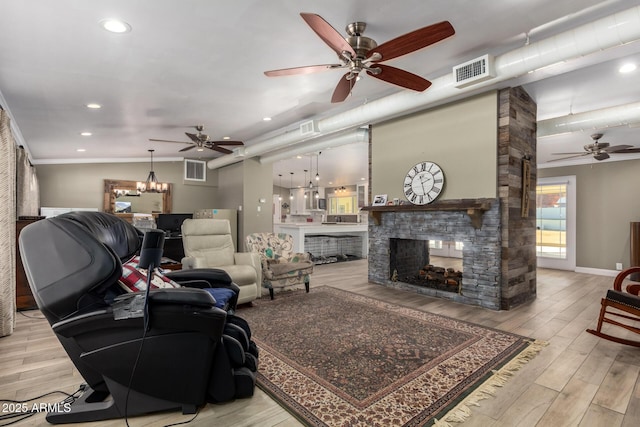 living room with a fireplace, light wood-type flooring, a notable chandelier, and ornamental molding