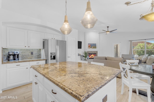 4301 E Abraham Ln, Phoenix, AZ 85050 - kitchen with stainless steel fridge with ice dispenser, ceiling fan, backsplash, light stone countertops, and white cabinetry
