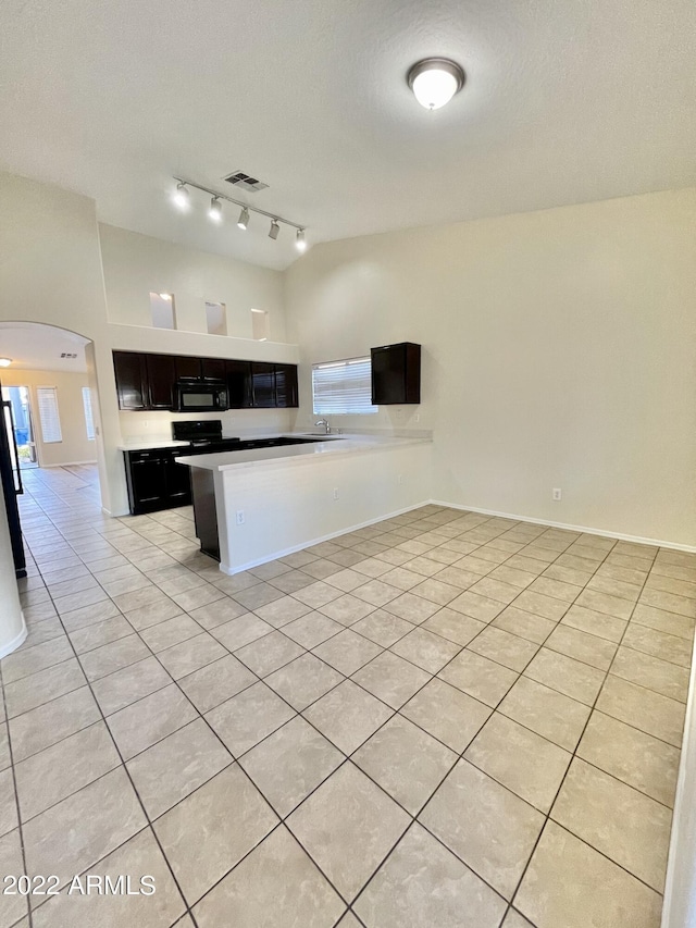 kitchen featuring sink, rail lighting, stainless steel refrigerator, light tile patterned flooring, and kitchen peninsula