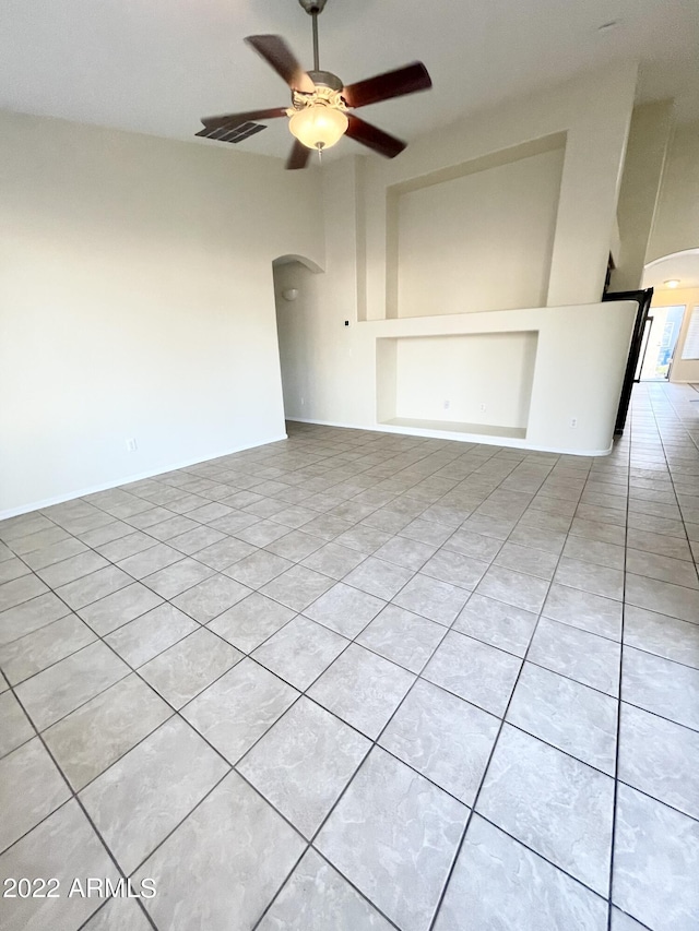 tiled spare room featuring built in shelves and ceiling fan