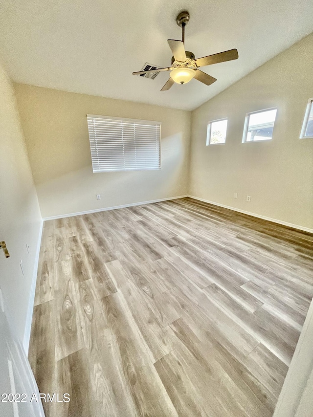 empty room with lofted ceiling, ceiling fan, and light hardwood / wood-style flooring