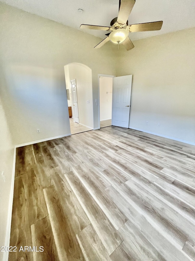 unfurnished bedroom featuring ensuite bathroom, ceiling fan, and light hardwood / wood-style floors