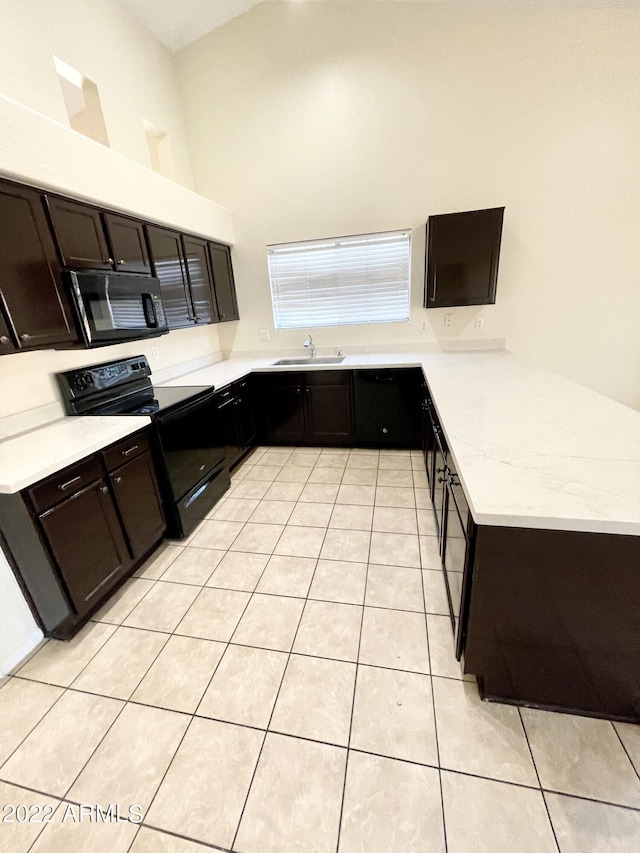 kitchen featuring sink, light tile patterned floors, dark brown cabinets, black appliances, and kitchen peninsula