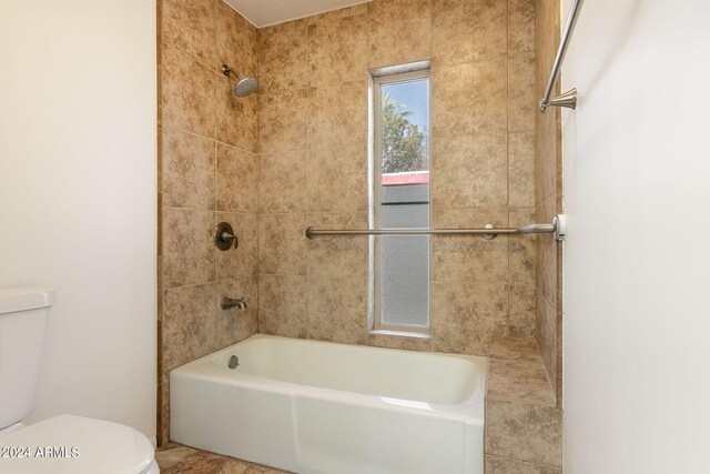 bathroom with toilet and tiled shower / bath