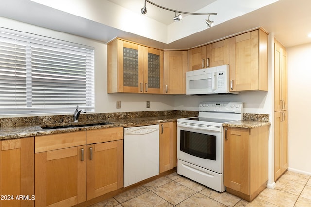 kitchen featuring sink, dark stone countertops, white appliances, and light tile patterned floors