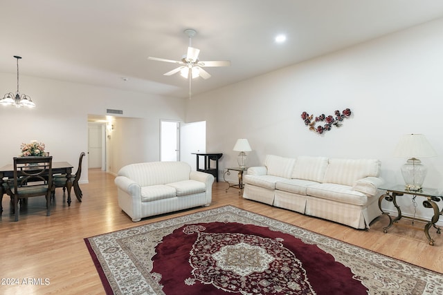 living room with light hardwood / wood-style floors and ceiling fan with notable chandelier