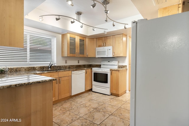 kitchen featuring sink, dark stone counters, white appliances, and light tile patterned floors