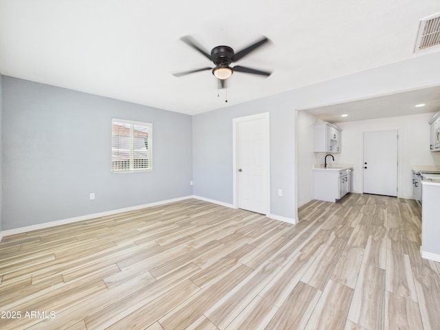 2628 W Marshall Ave, Phoenix, AZ 85017 - unfurnished living room with visible vents, baseboards, a sink, light wood-type flooring, and a ceiling fan
