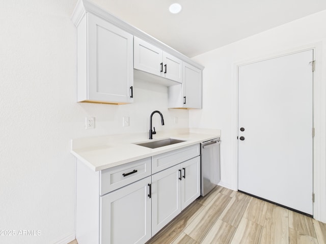 2628 W Marshall Ave, Phoenix, AZ 85017 - kitchen featuring light wood-style flooring, white cabinets, a sink, light countertops, and stainless steel dishwasher