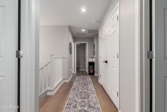 corridor featuring light wood finished floors, baseboards, visible vents, an upstairs landing, and recessed lighting