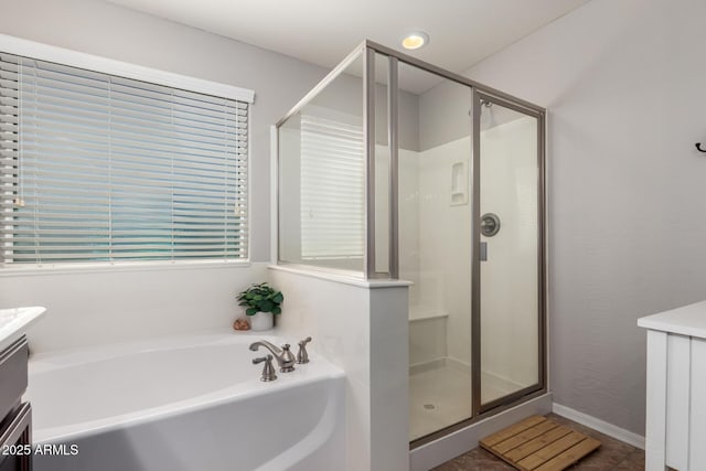 bathroom with a shower stall, a bath, and vanity