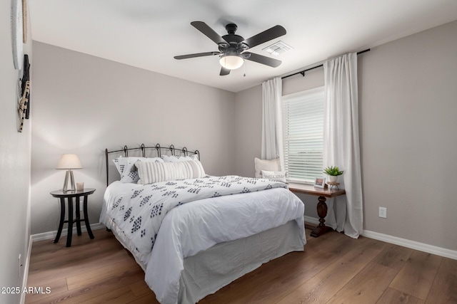 bedroom featuring a ceiling fan, visible vents, baseboards, and wood finished floors