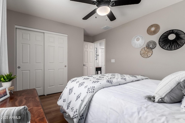 bedroom featuring dark wood-style floors, a closet, visible vents, and ceiling fan