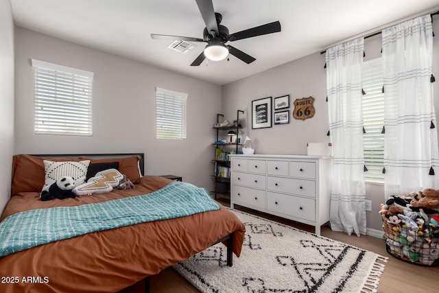 bedroom with light wood-style floors, ceiling fan, and visible vents