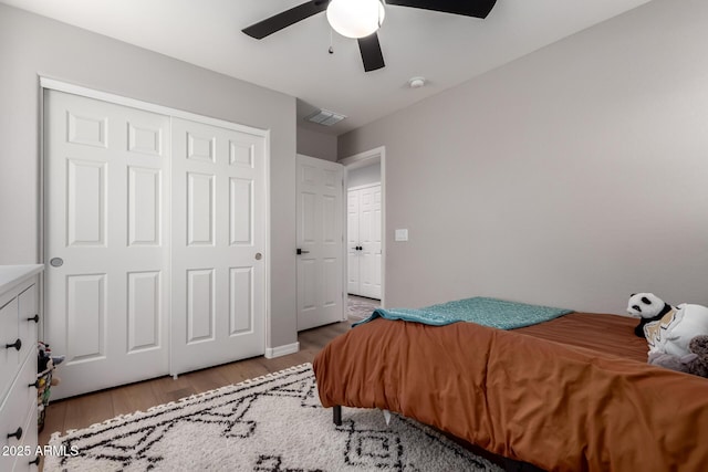 bedroom featuring a ceiling fan, a closet, visible vents, and wood finished floors