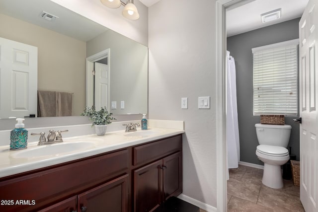 full bathroom with baseboards, a sink, toilet, and double vanity