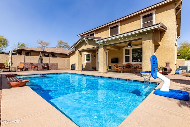 view of swimming pool featuring central AC unit, fence, a ceiling fan, a fenced in pool, and a patio area