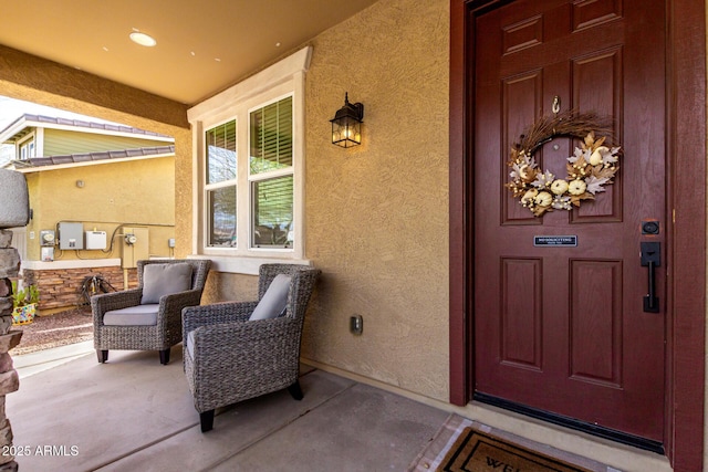 view of exterior entry with covered porch and stucco siding