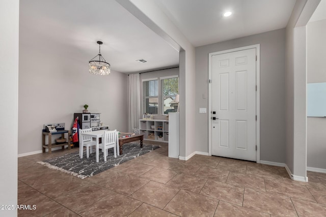 tiled entrance foyer with visible vents, a notable chandelier, and baseboards