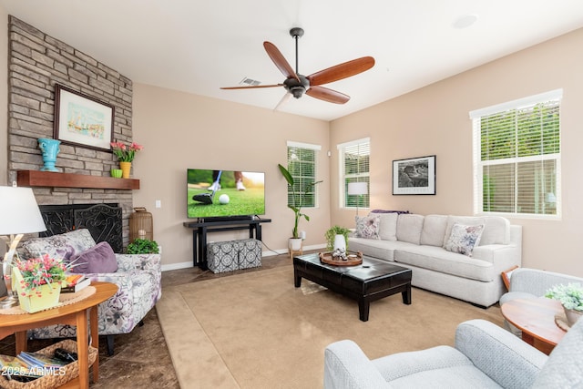 living room featuring ceiling fan and a stone fireplace