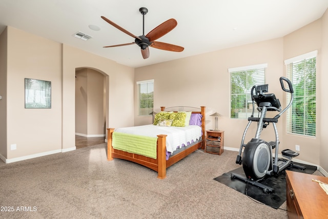 bedroom featuring arched walkways, baseboards, visible vents, and ceiling fan